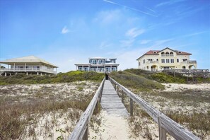 A wooden boardwalk leading to three beachfront properties with distinct architectural styles. - LEAVE YOUR WORRIES SURFSIDE. Take the private boardwalk and you're only steps from the beach. (St. George Island)