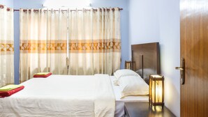 Een hotelkamer met een bed, nachtkastje, lamp en gordijnen.