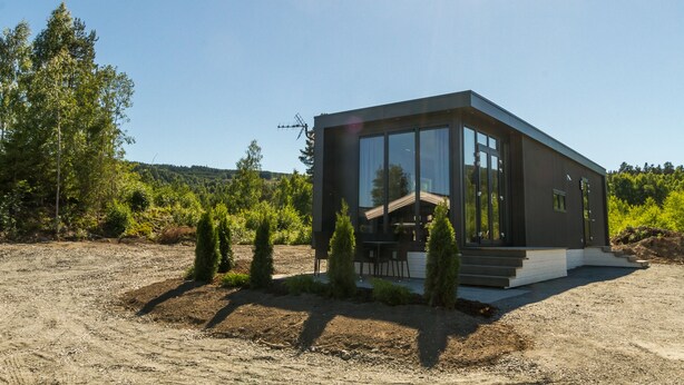 A modern house with large windows, a wooden deck, and a dirt driveway. - Sveastranda Camping (Gjovik)