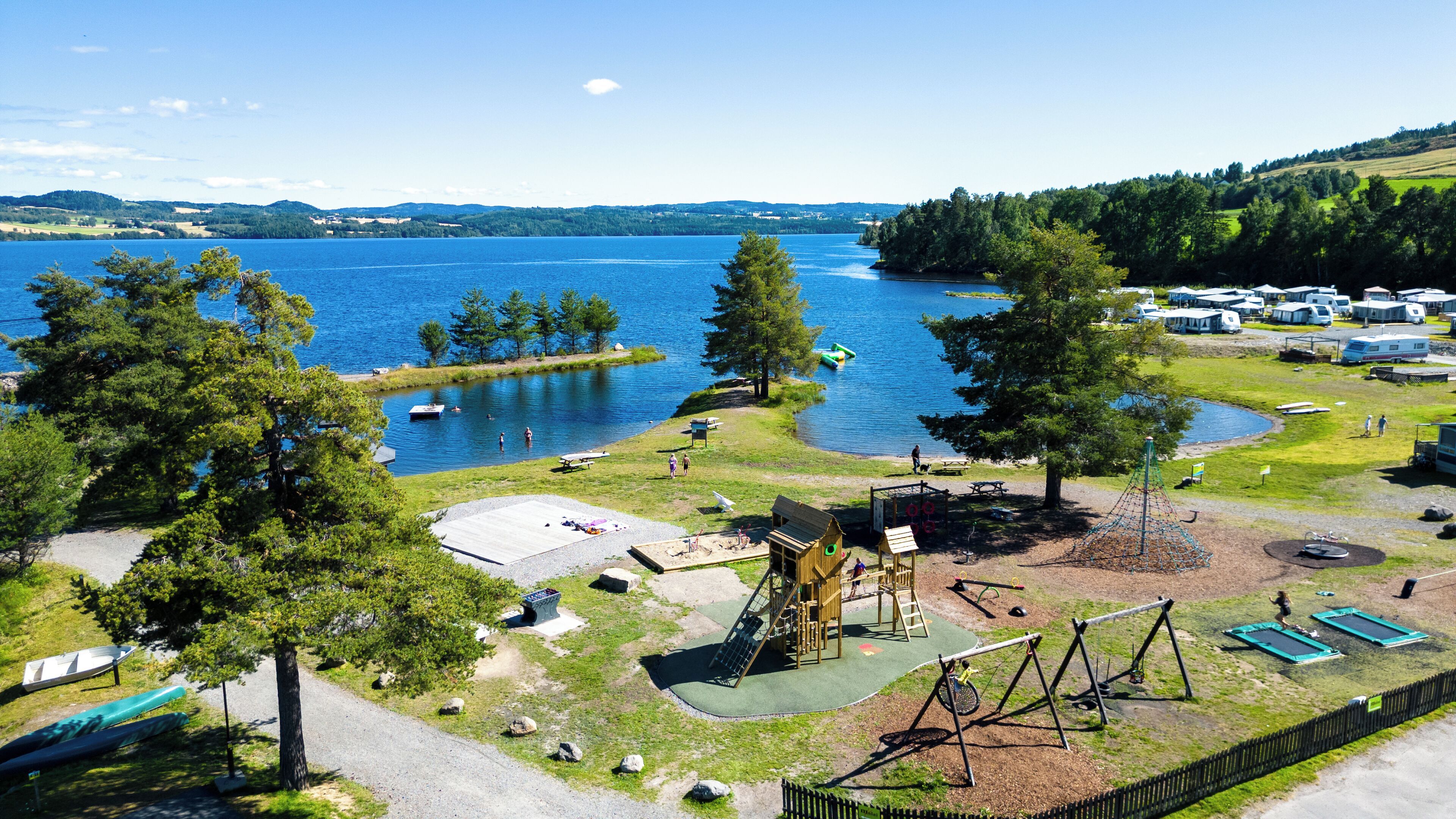 A lakeside campground with picnic areas, a playground, and RV parking.