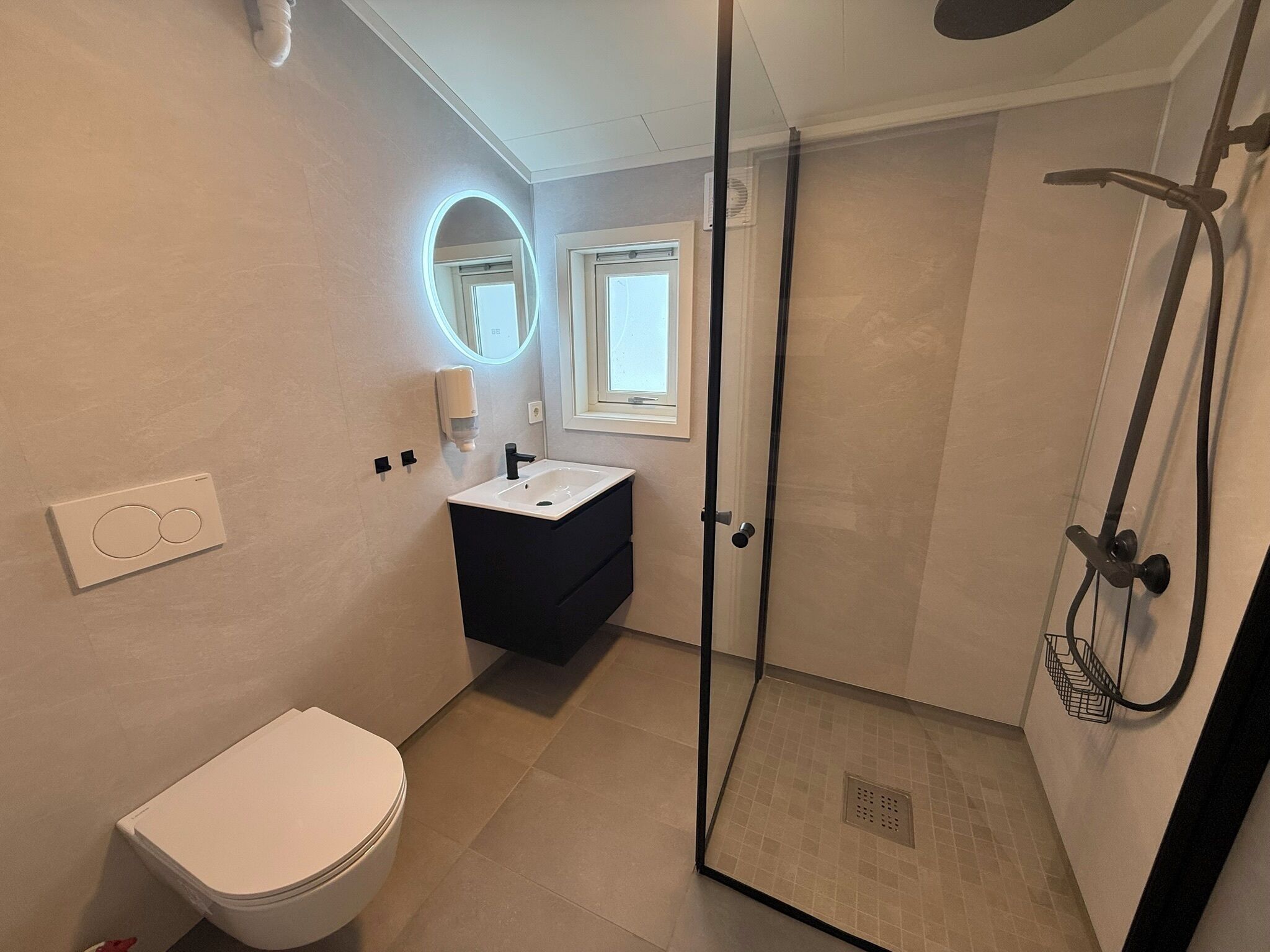 A modern bathroom with a toilet, sink, and shower.