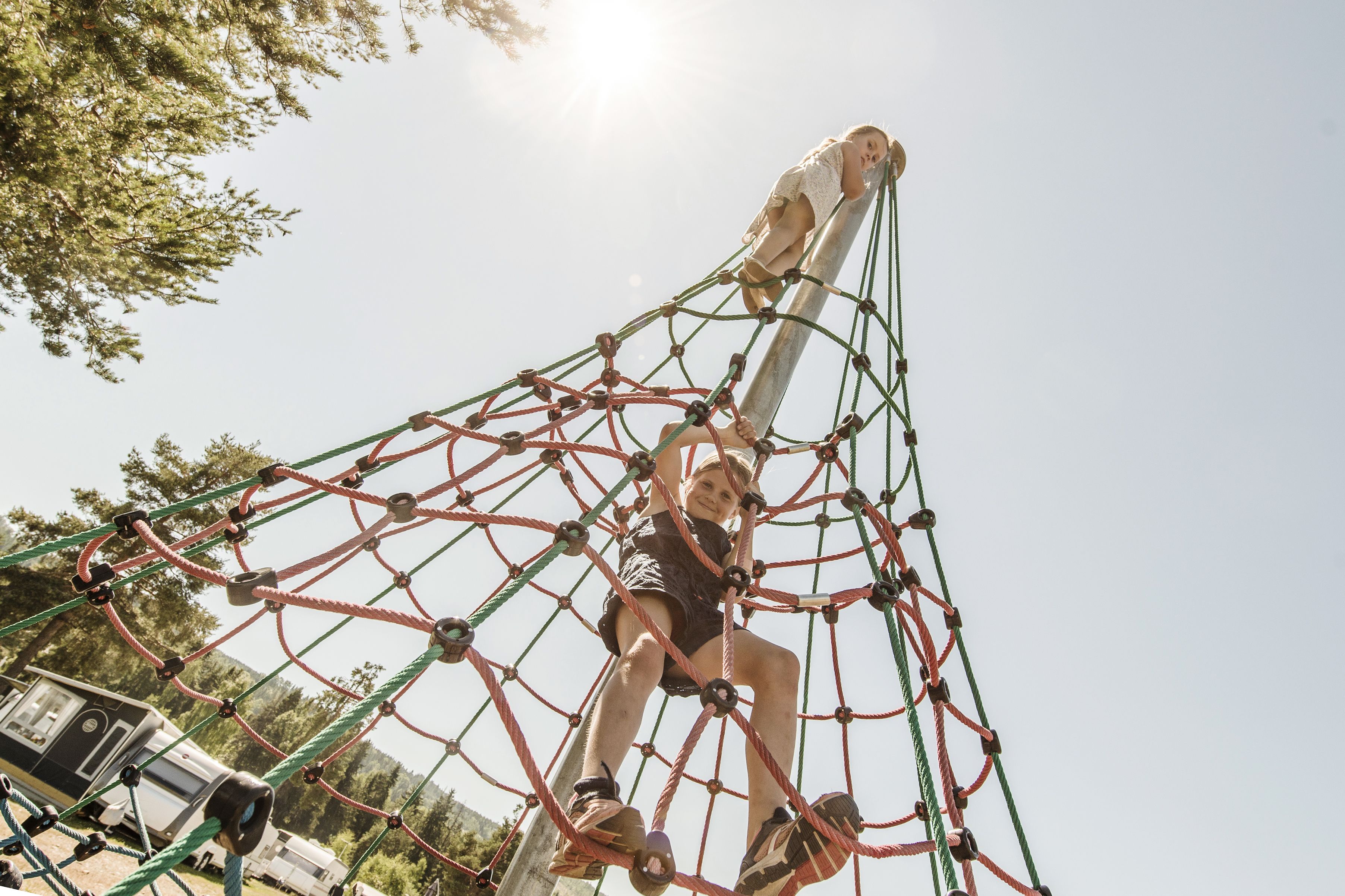 A person climbing a rope net structure outdoors.