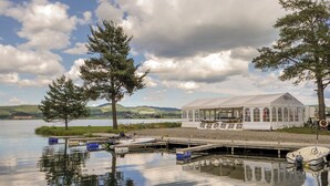 A lakeside setting with a white tent and docked boats. - Sveastranda Camping (Gjovik)