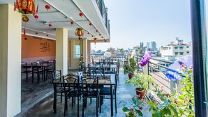 An outdoor dining area with tables and chairs, red lanterns, and potted plants. - Golden Gate China Town Hotel (Yangon)