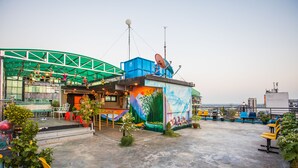 A rooftop terrace with seating, a mural, and a green structure. - Golden Gate China Town Hotel (Yangon)