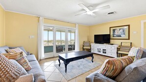 Ein Wohnzimmer mit einer Couch, einem Couchtisch, einem Fernseher und einem Deckenventilator.
