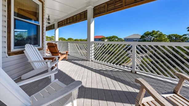 A covered porch with white Adirondack chairs, a wooden bench, and a white railing. - CREATE THE PERFECT VACATION experience for the whole family in Pretty Woman! (St. George Island)