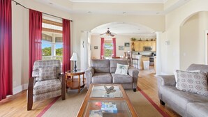 A spacious living area with a sofa, armchair, and coffee table, leading to a kitchen and dining area. - CREATE THE PERFECT VACATION experience for the whole family in Pretty Woman! (St. George Island)