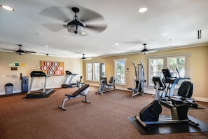 Une salle de sport équipée de tapis de course, de vélos elliptiques et d'appareils de musculation.