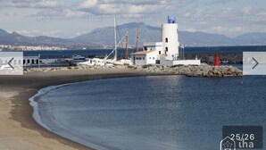 Ein Küstengebäude mit einem Leuchtturm, in Strandnähe und am Meer gelegen.