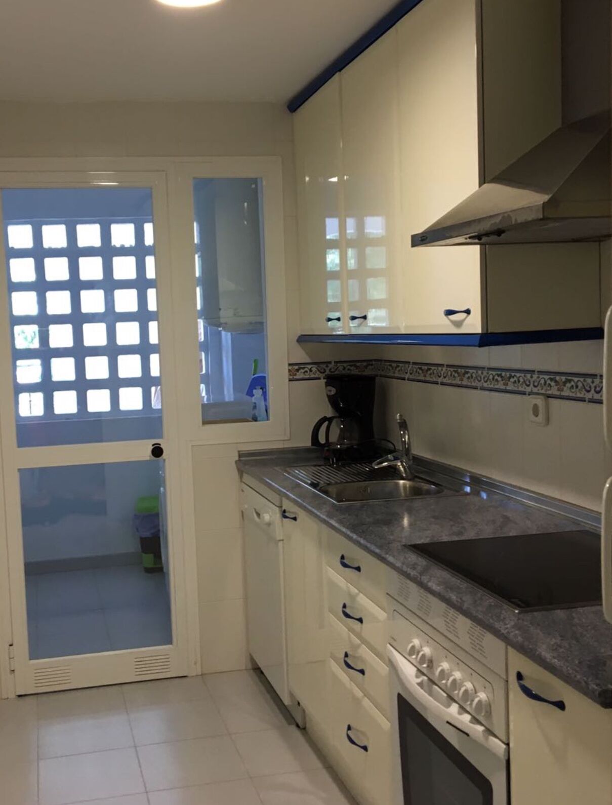 Een keuken met witte kasten, een roestvrijstalen spoelbak en een fornuis.