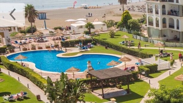Ein Resort mit großem Swimmingpool, Zugang zum Strand und einem mehrstöckigen Gebäude mit Balkonen.