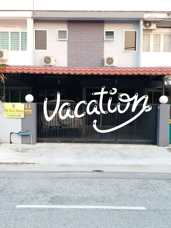 A building with a sign that reads "SK Rest Home" and a large gate with the word "Vacation" written on it.