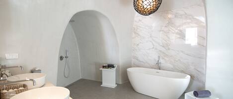 A modern bathroom with a freestanding bathtub, a large oval sink, and a small white stool.