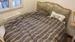A bedroom with a bed, a radiator, a window, and a bedside lamp. - Quiet and bright apartment near the shops (Berck)
