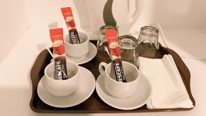 A tray with four white cups and saucers, each containing a packet of coffee labeled "ESCAPE Blend & Brew." There is a white teapot and two glass carafes on the tray. - SS Hotel Seremban (Seremban)