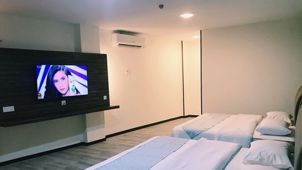 A hotel room with a flat-screen TV mounted on the wall, two beds with white bedding, a wooden floor, and an air conditioning unit on the wall. - SS Hotel Seremban (Seremban)