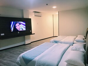 A hotel room with a flat-screen TV mounted on the wall, two beds with white bedding, a wooden floor, and an air conditioning unit on the wall. - SS Hotel Seremban (Seremban)