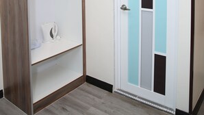 A room with a wooden wardrobe, a white door with a blue and gray panel, and a light-colored floor. - SS Hotel Seremban (Seremban)