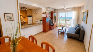 A modern living room with a sofa, dining table, and kitchen area with a view of the sea. - LOS RISCOS 2 (La Pineda)
