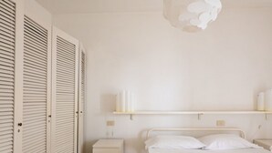 Een slaapkamer met een bed, nachtkastjes, een kledingkast en een plank met spullen.