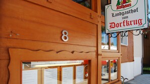 Un bâtiment en bois sur lequel est apposée une enseigne indiquant qu’il s’agit d’un « Landgasthof zum Dorfkrug ».