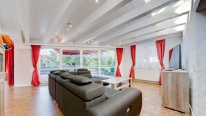Un salon moderne avec un canapé d’angle, une table basse en bois et un meuble pour la télévision.