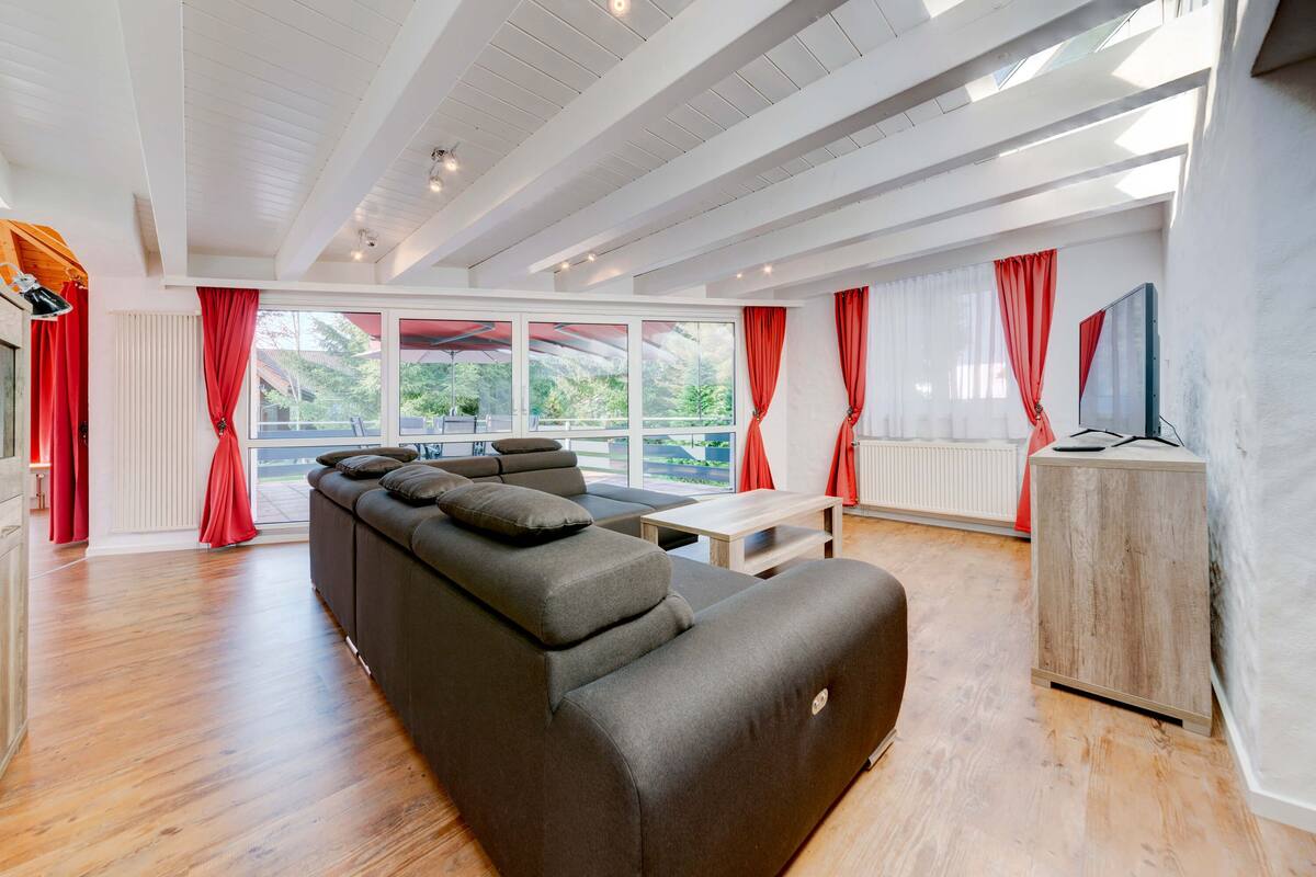 A modern living room with a sectional sofa, a wooden coffee table, and a TV stand.