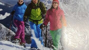 Tres personas esquiando en una pendiente nevada con árboles al fondo.