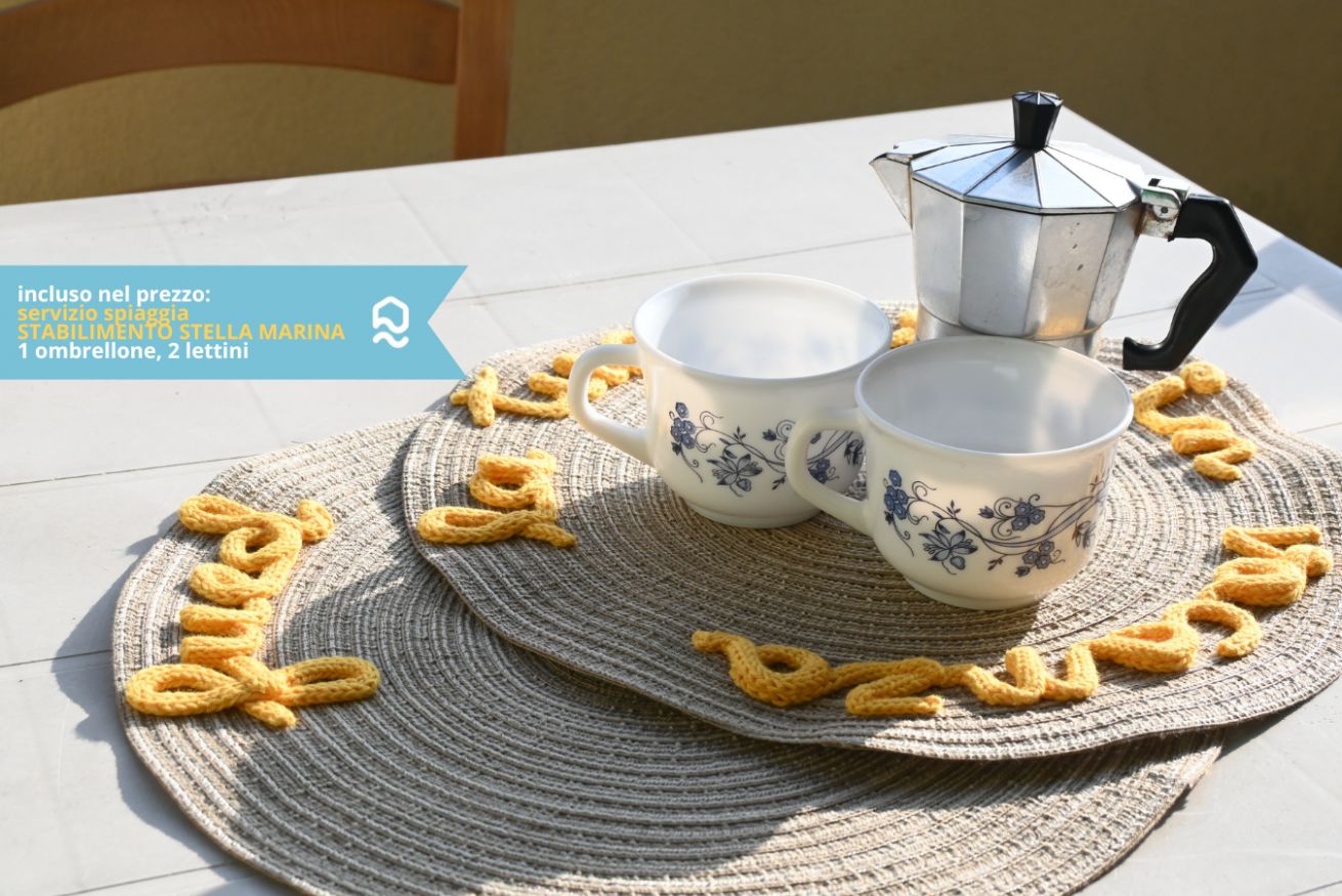 Une table avec une cafetière, deux tasses et un set de table à motifs.