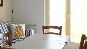 A dining area with a white table, striped sofa, and two wooden chairs. - N148 - Numana, new three-room apartment with terrace 350mt from the sea (Numana)
