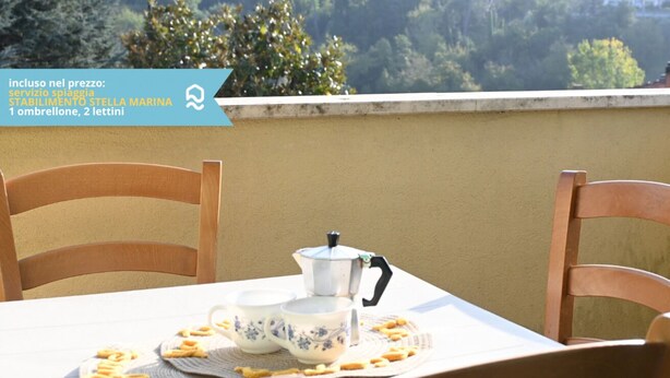 A table with a teapot and cups, a mat, and some snacks on a balcony overlooking a forested area. - N148 - Numana, new three-room apartment with terrace 350mt from the sea (Numana)