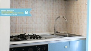 A kitchen with a gas stove, sink, and blue cabinets. - N148 - Numana, new three-room apartment with terrace 350mt from the sea (Numana)