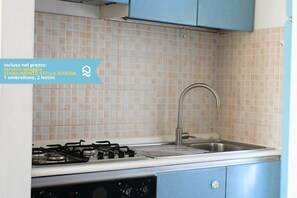 A kitchen with a gas stove, sink, and blue cabinets. - N148 - Numana, new three-room apartment with terrace 350mt from the sea (Numana)