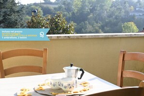 A table with a teapot and cups, a mat, and some snacks on a balcony overlooking a forested area. - N148 - Numana, new three-room apartment with terrace 350mt from the sea (Numana)