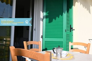 A room with a table, chairs, a window with a view, and a green door. - N148 - Numana, new three-room apartment with terrace 350mt from the sea (Numana)