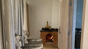 Un pasillo con chimenea, un sofá y una puerta que da a otra habitación.