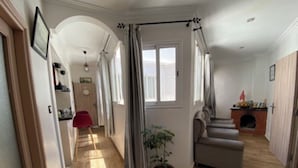 Un salón amplio con chimenea, una planta en maceta y un sofá gris.