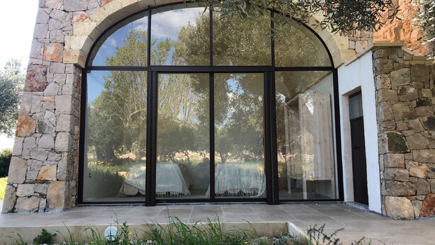 A stone facade with a large arched window and a door. - SAN GREGORIO VILLA WITH SECULAR OLIVE GROVE, GARDEN AND PORCH (Patù)
