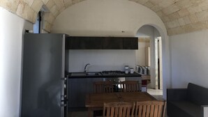 A compact kitchen with a built-in stove, dark cabinets, and a wooden dining table. - SAN GREGORIO VILLA WITH SECULAR OLIVE GROVE, GARDEN AND PORCH (Patù)