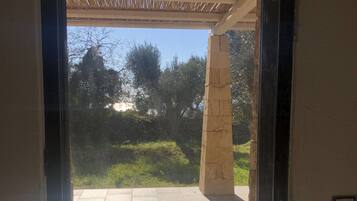 An open doorway leading to a patio area with a tiled floor and a pergola overhead.