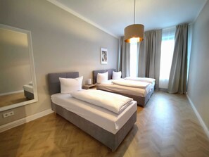 Habitación de hotel moderna con dos camas individuales, un espejo grande e iluminación en el techo.