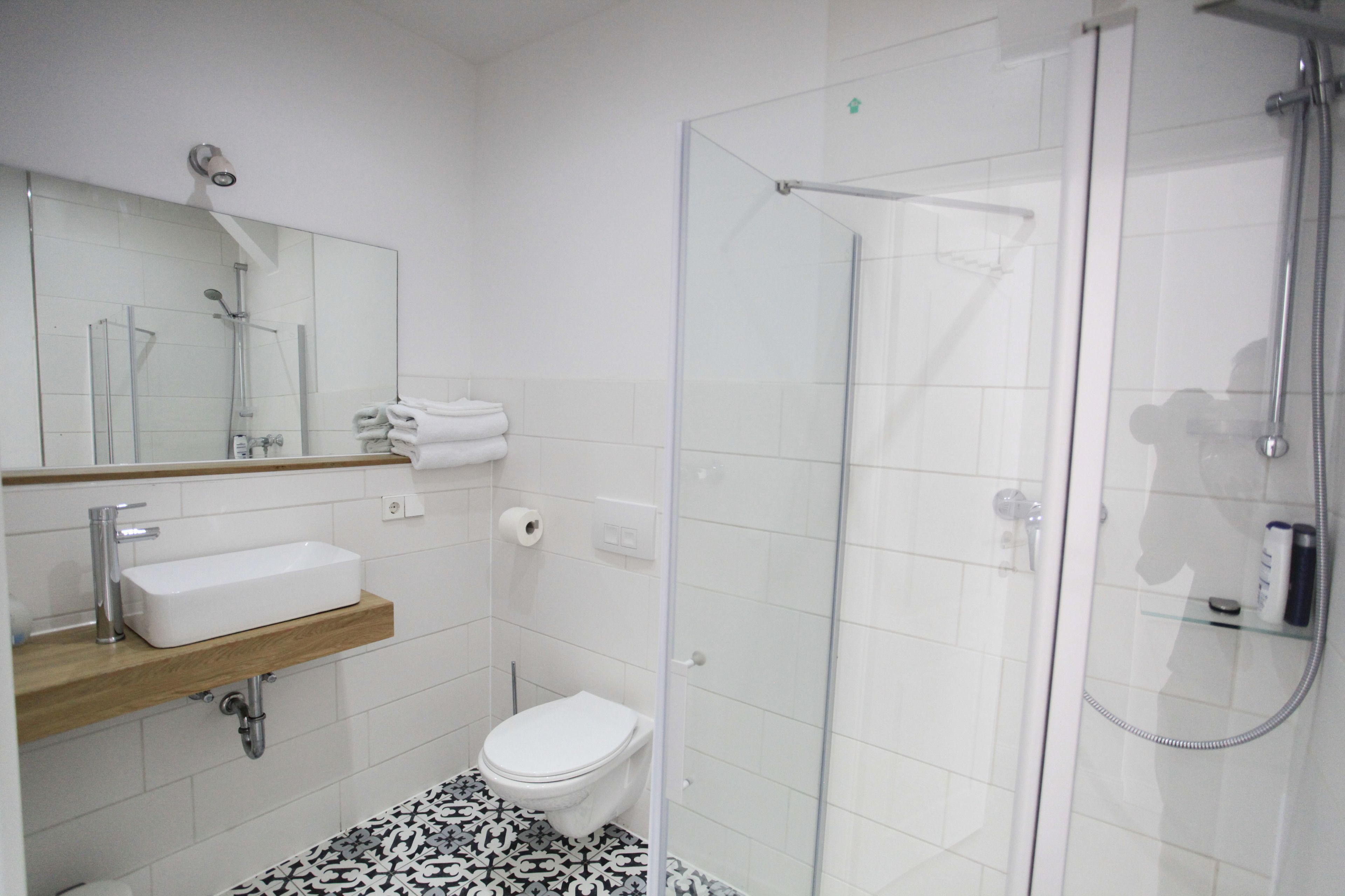 A modern bathroom with a glass-enclosed shower, a white sink with a wooden countertop, and a toilet.