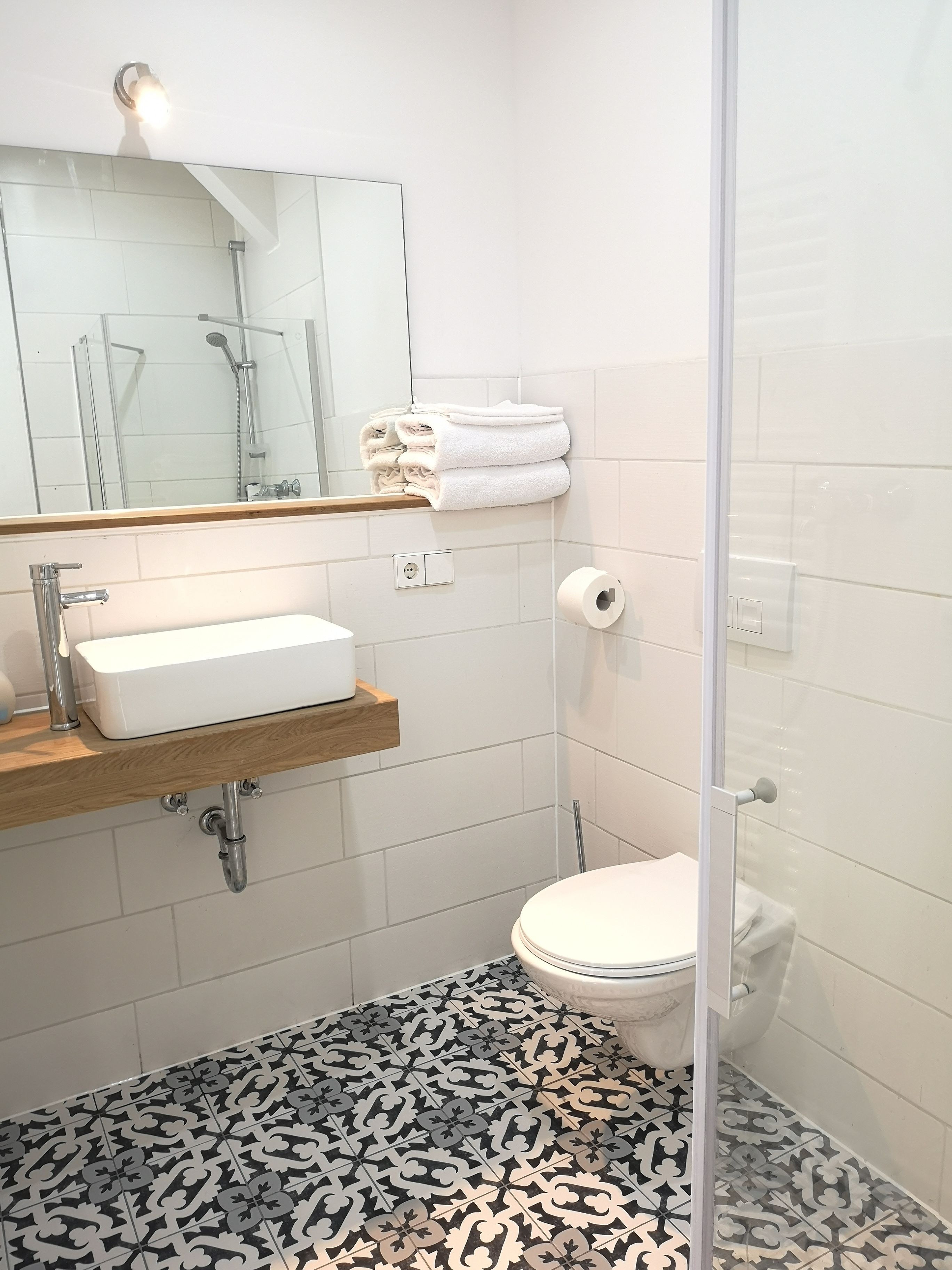 A modern bathroom with a white sink, a toilet, and a shower area.