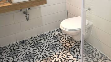 A modern bathroom with a white sink, a toilet, and a shower area.