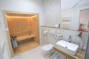 Une salle de bain moderne avec un espace de douche en bois, un lavabo blanc et un mur recouvert de carreaux de marbre.