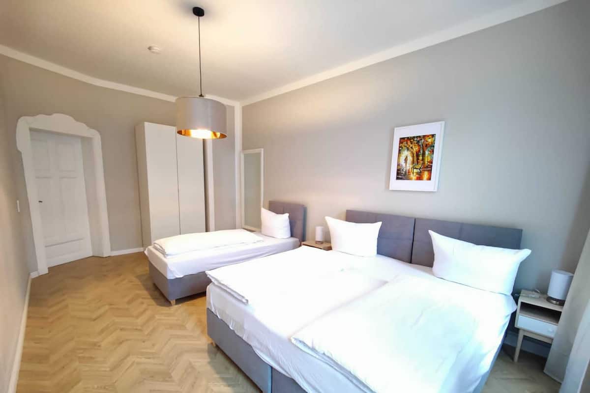 Un dormitorio moderno con dos camas, un espejo grande y una lámpara en el techo.