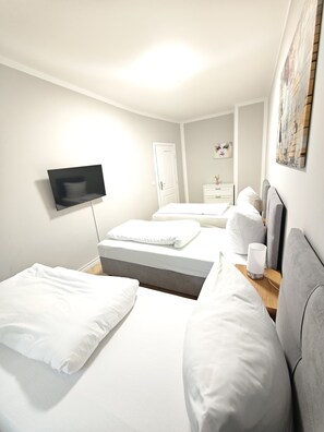 Una habitación de hotel con cama, mesita de noche, lámpara y un televisor de pantalla plana montado en la pared.