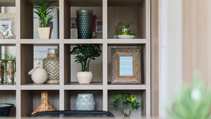 A wooden shelf with various decorative items including plants, vases, and framed pictures. - GRAND BASE Mojiko (Kitakyushu)