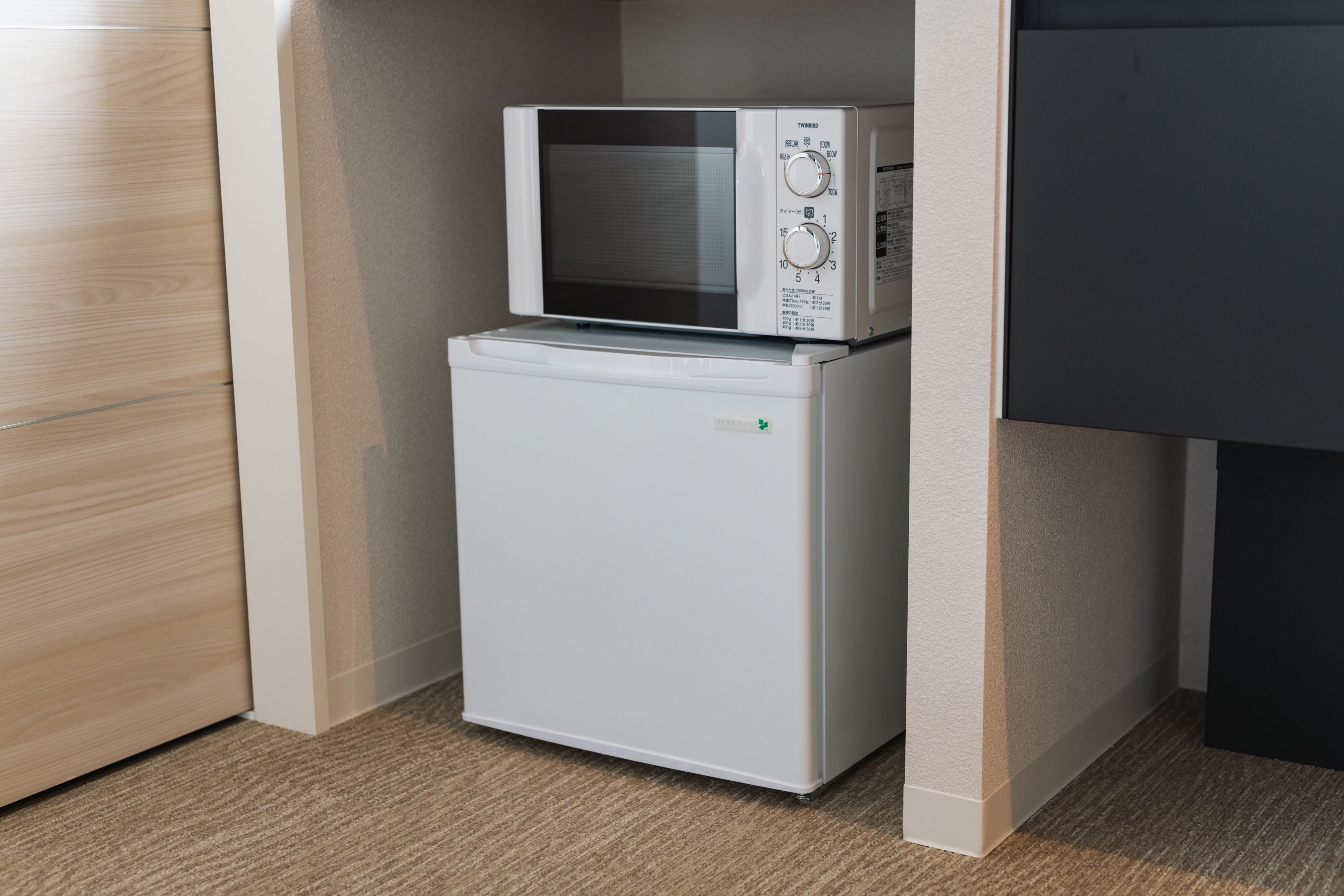 A compact kitchen with a microwave and a small refrigerator.